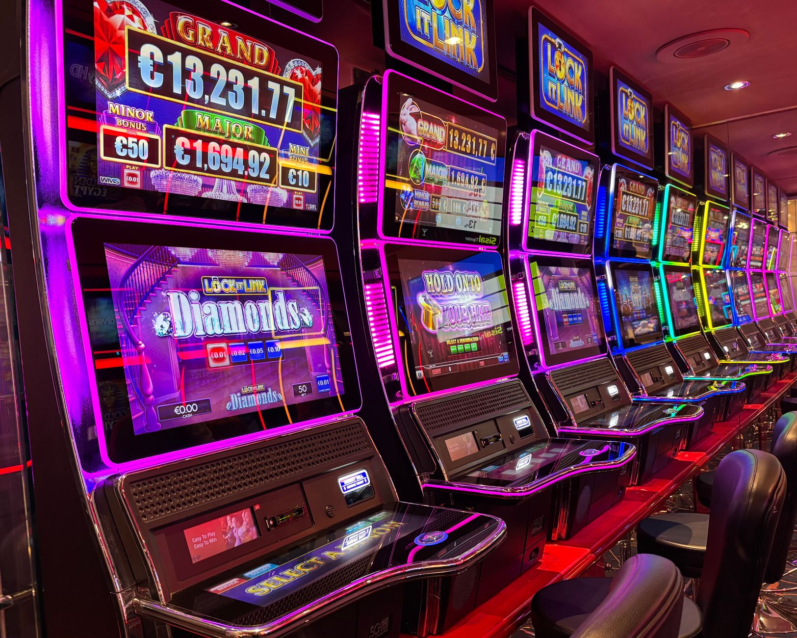 Endless rows of brightly lit slot machines create complex aisles that a cleaning robot must navigate on a casino floor.