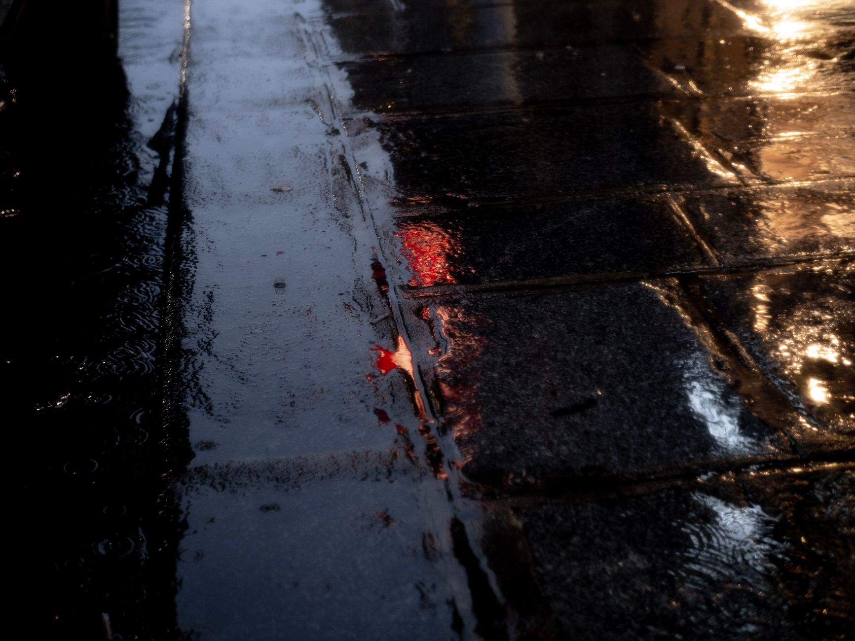 A freshly cleaned, wet stone plaza at night, reflecting the warm glow of surrounding lights, showcasing a perfectly clean surface.