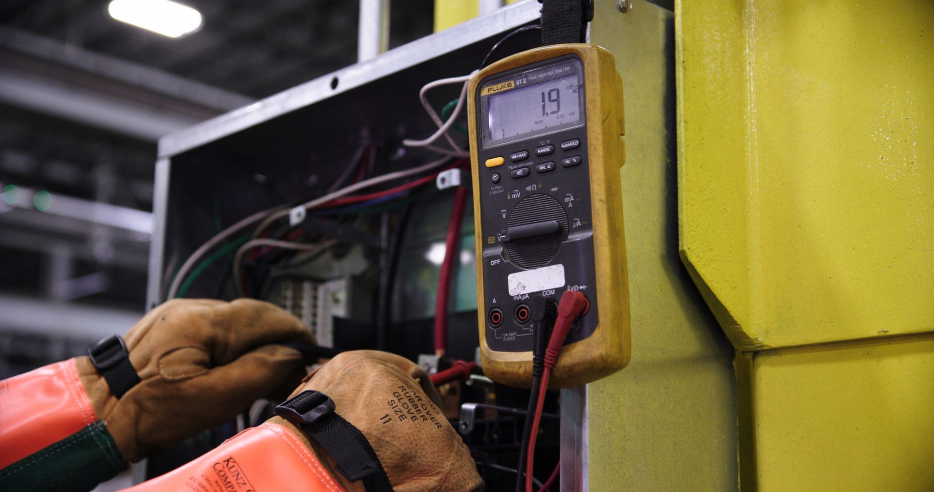 A technician wearing protective gloves carefully cleans electrical contact surfaces with an approved cloth.