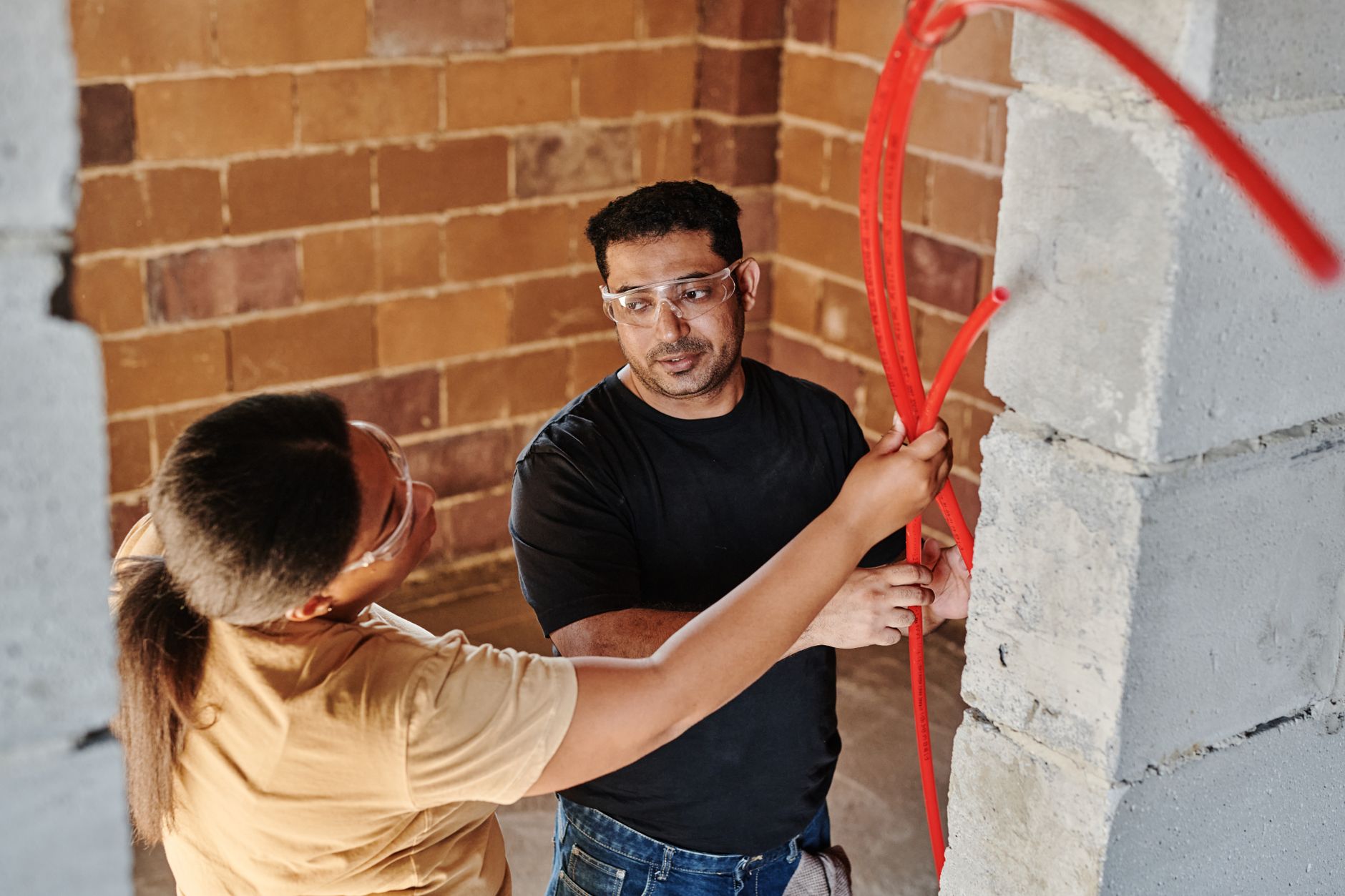 A maintenance worker inspects a water hose and coupling for leaks, wear, and loose connections.
