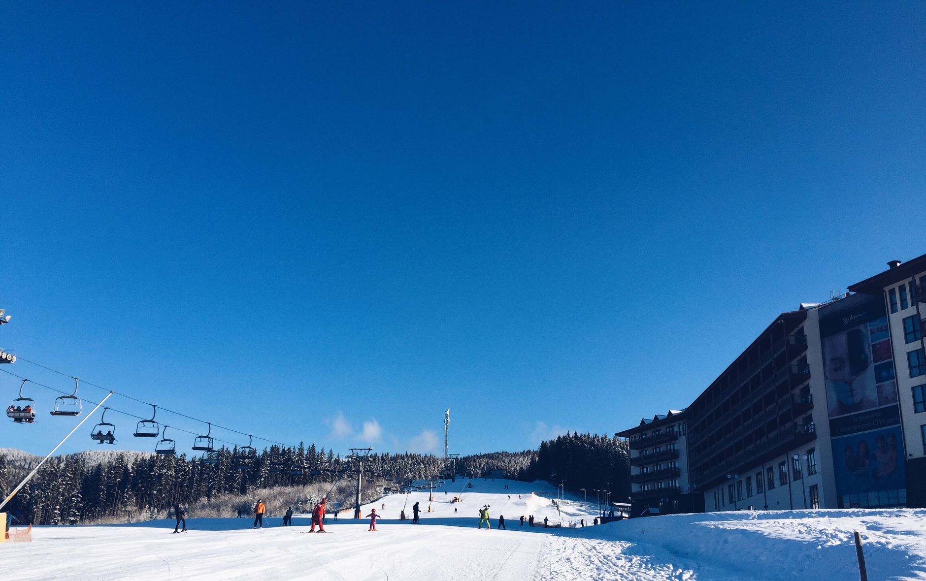 Exterior of a ski resort hotel at the base of snowy slopes.