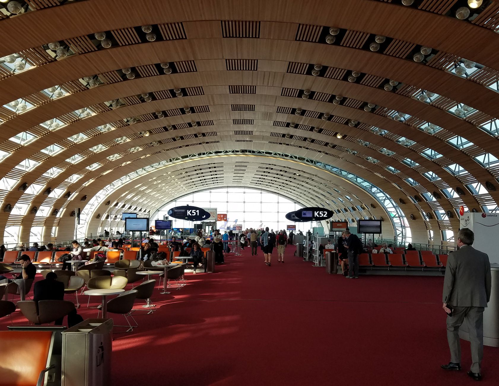 Airport gate hold room with carpeted seating and large windows