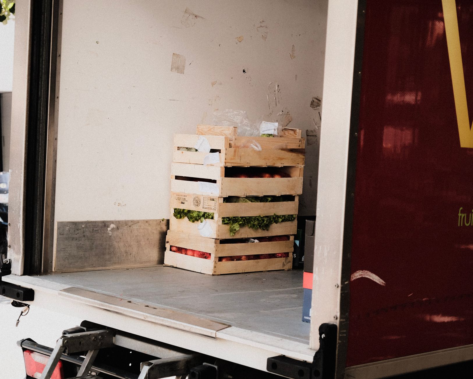 A fleet of branded grocery delivery trucks lined up at a fulfillment center loading dock, ready to transport orders.