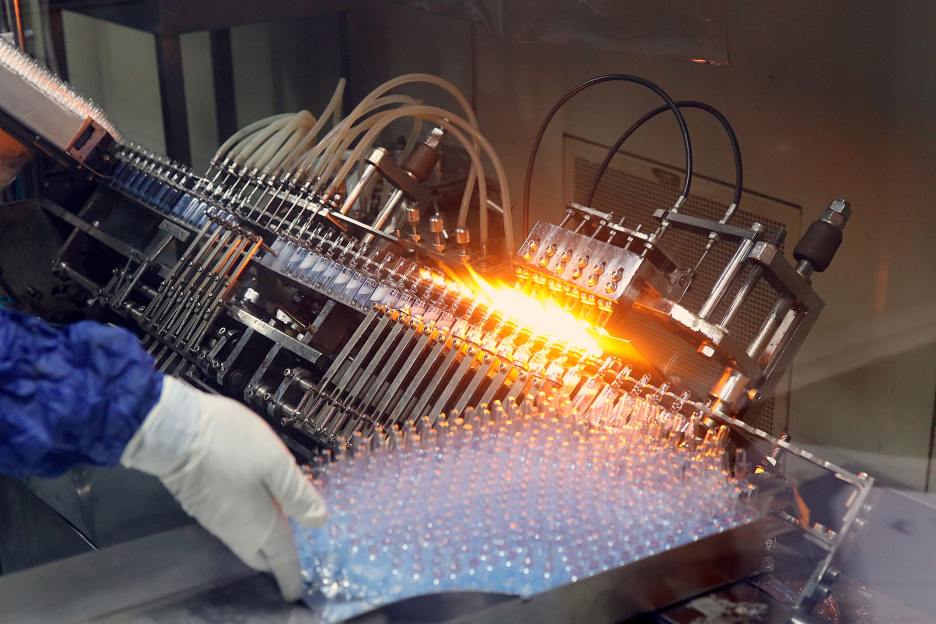 A line of sterile glass vials being processed, illustrating the delicate and precise aseptic tasks that can be automated.