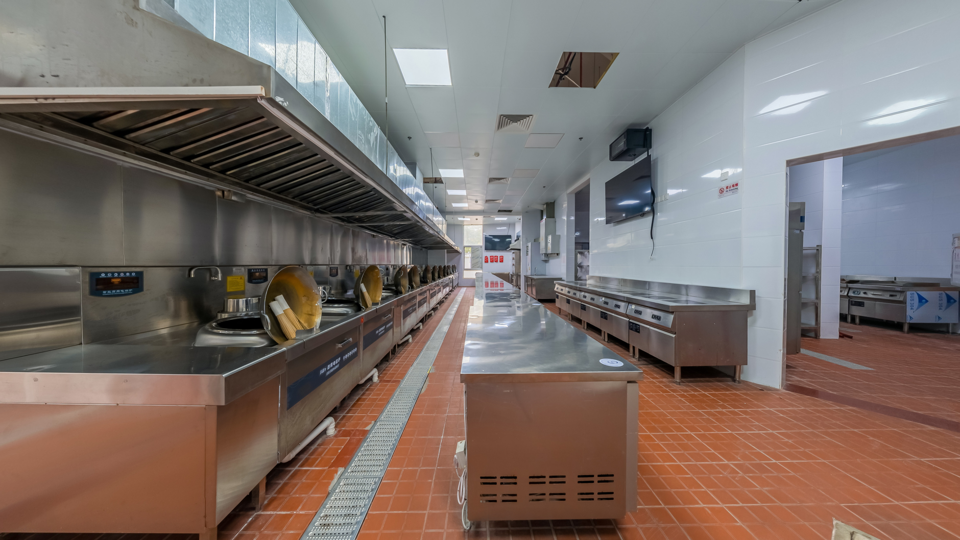 The durable, tiled floor of a commercial kitchen, an environment that requires specialized autonomous scrubbers to handle grease and spills.