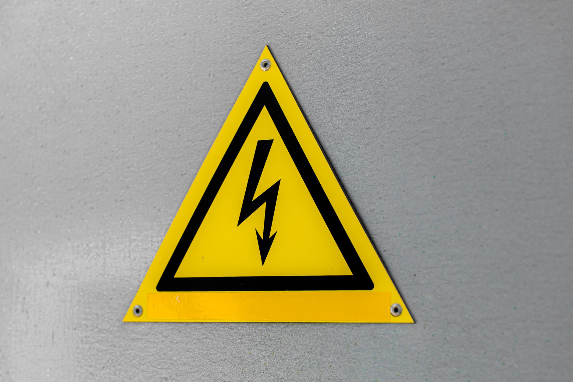 An electrician follows lockout-tagout precautions beside energized electrical equipment.