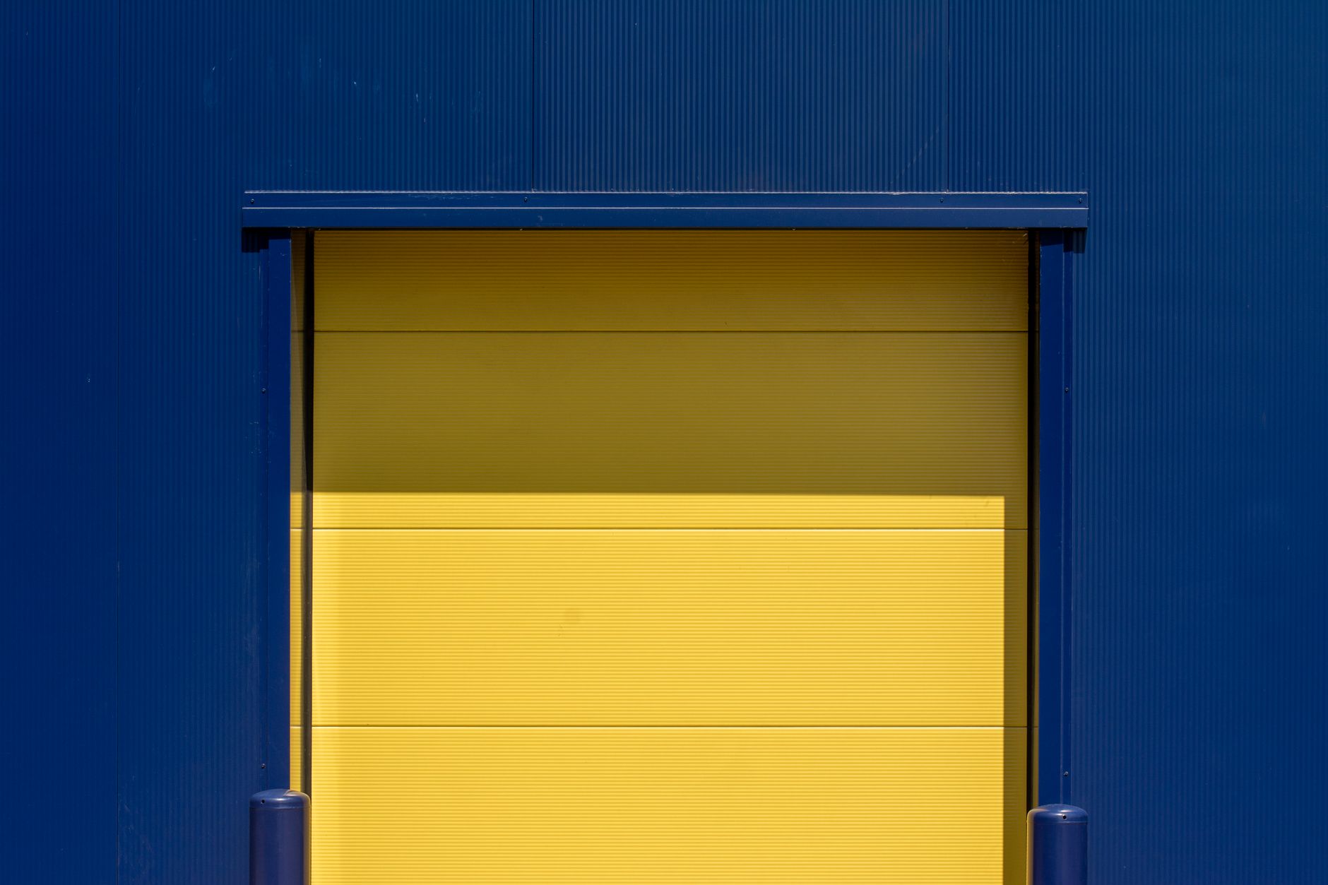 Sunlight streams into a warehouse through a large, open loading bay door, illustrating the variable lighting conditions that can challenge vision-based AMRs.