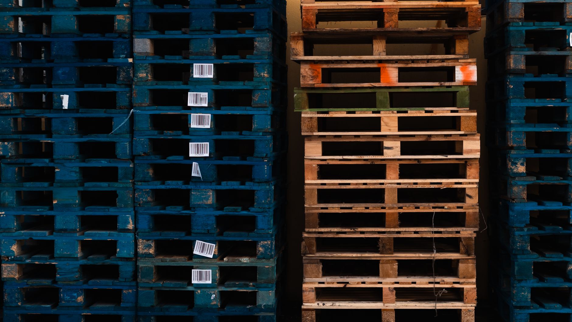Neatly stacked wooden pallets in a warehouse, representing the heavy payload capacity required for certain AMR tasks.