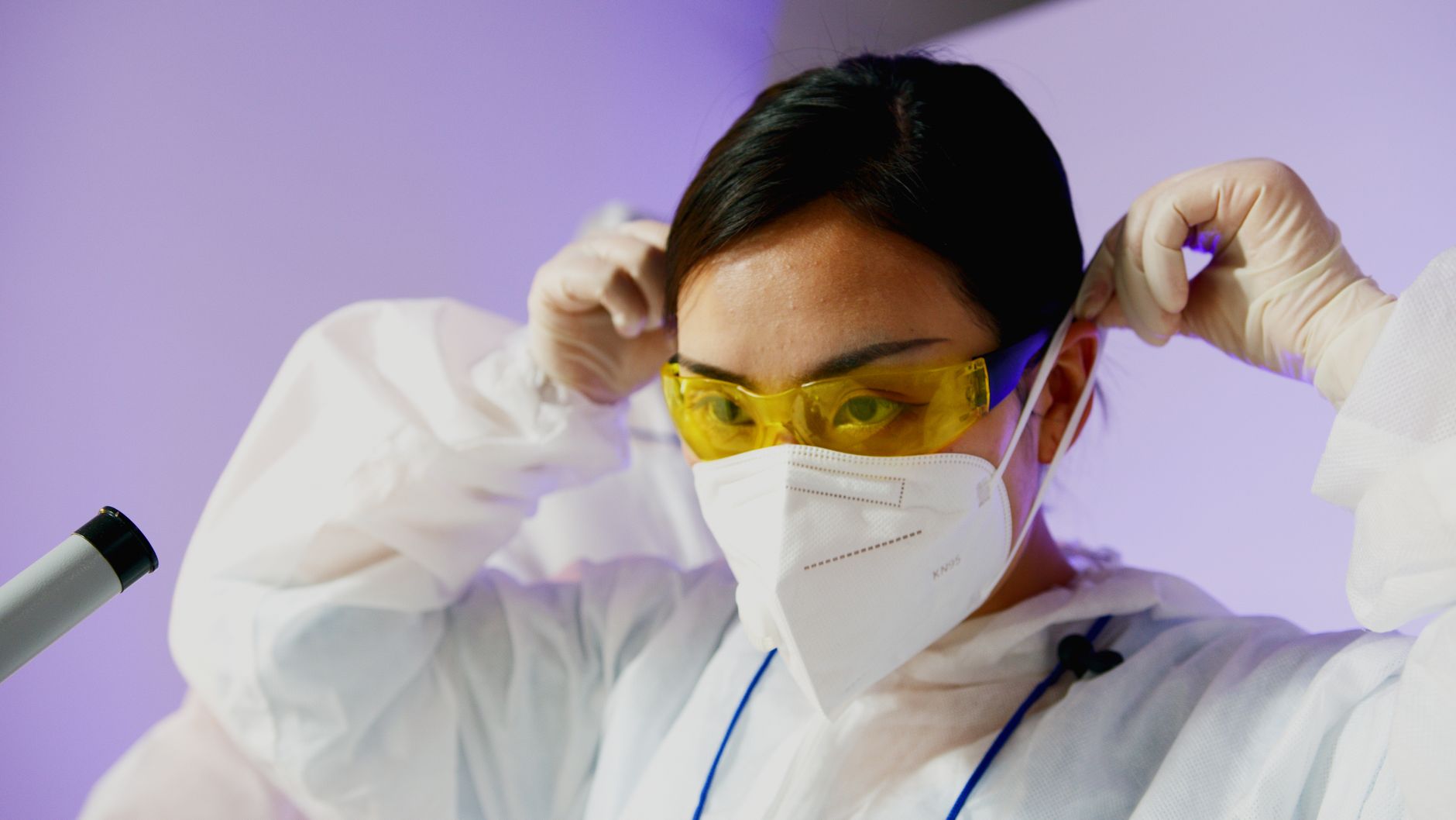 A laboratory worker wearing protective gloves handles clinical specimens within a controlled workspace.