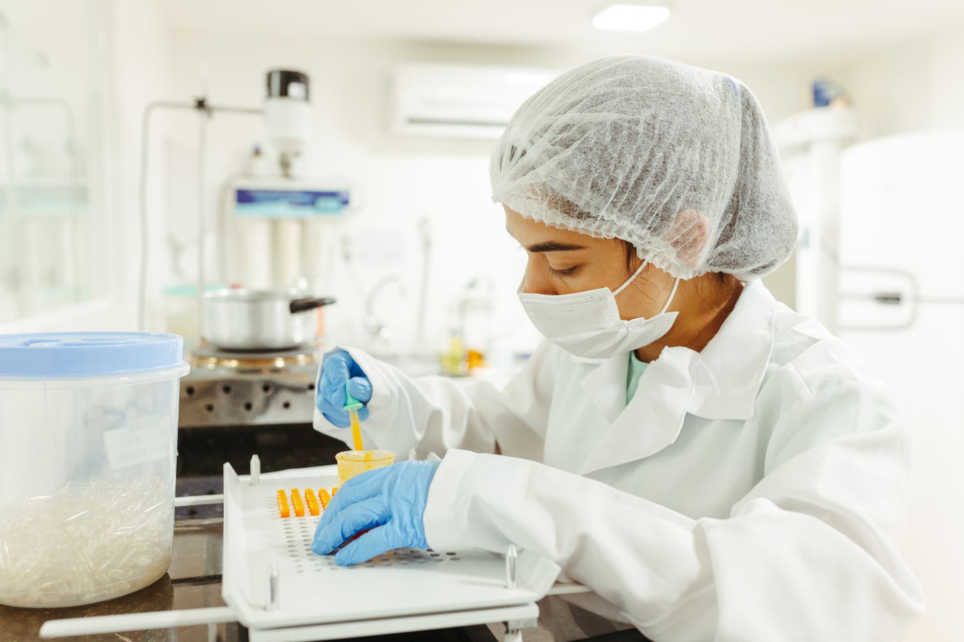 A clinical laboratory scientist examines labeled specimen tubes at a diagnostic testing bench.