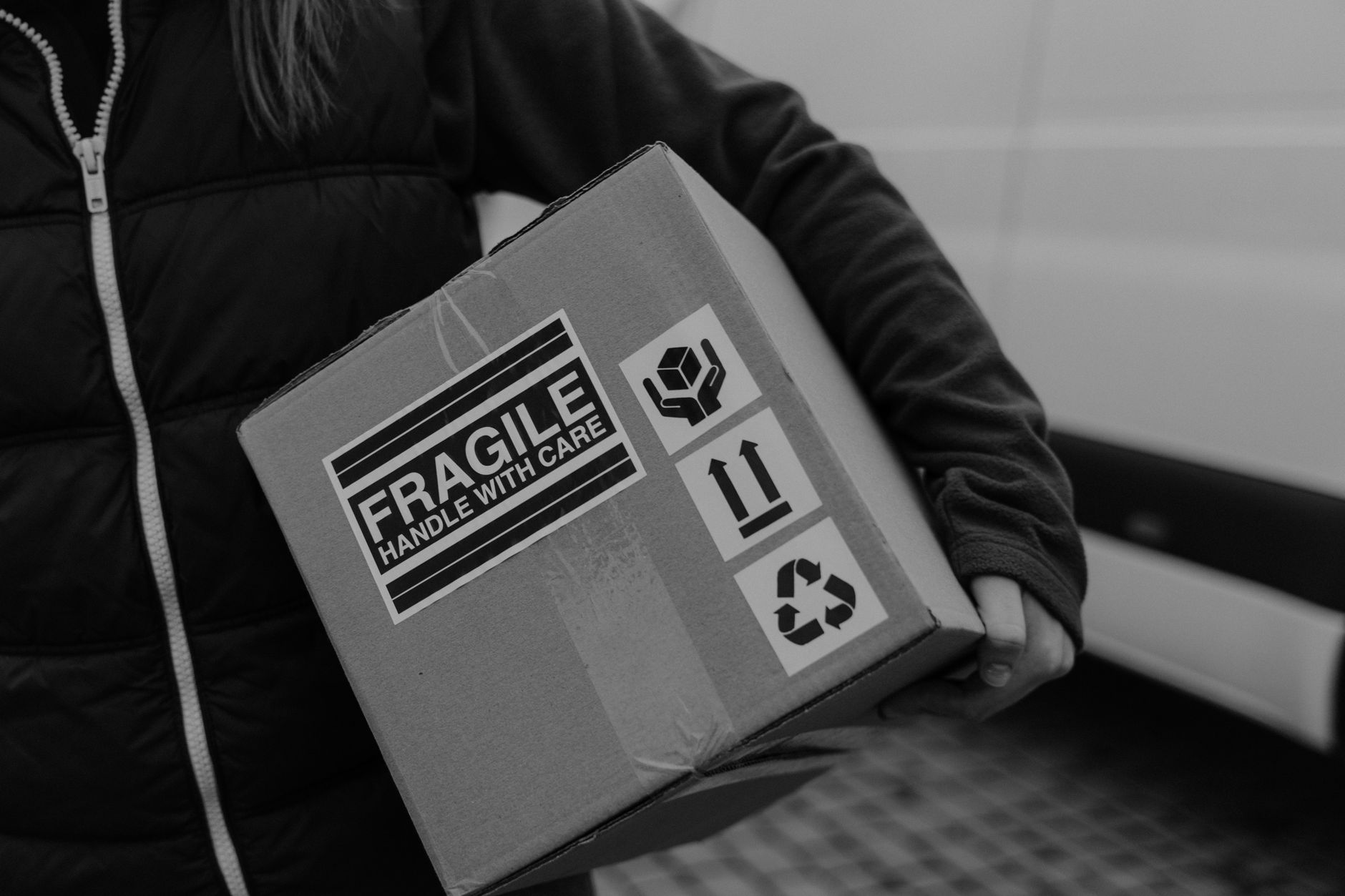 A worker carefully grips a cardboard box, suggesting the gentle but firm handling required by an advanced end-of-arm tool.