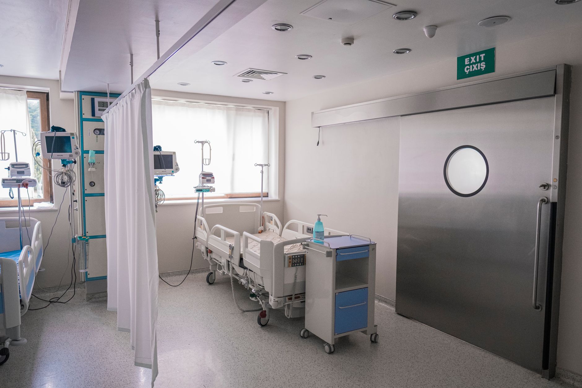 A hospital isolation-room doorway with wall-mounted controls and signage visible beside it.