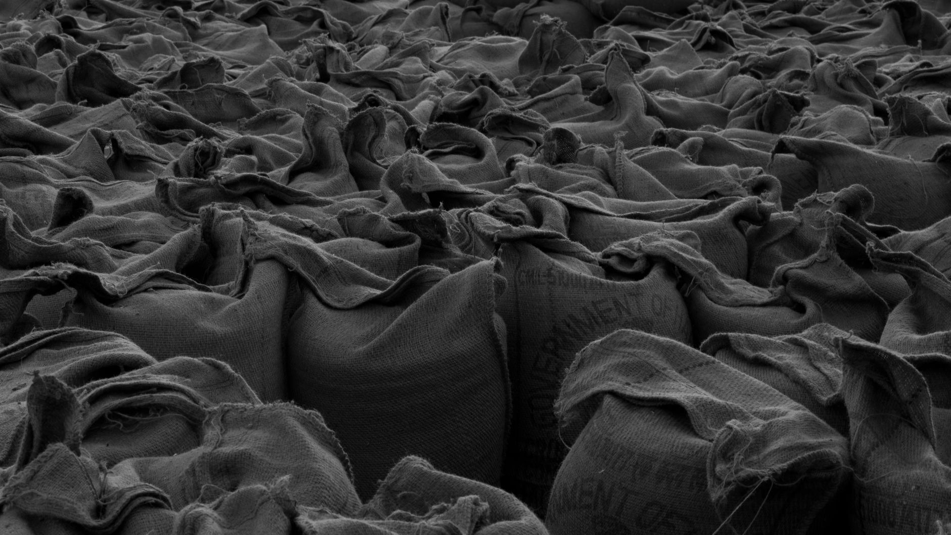Stacked potato sacks in a storage bay where dust and soil collect around pallet traffic.