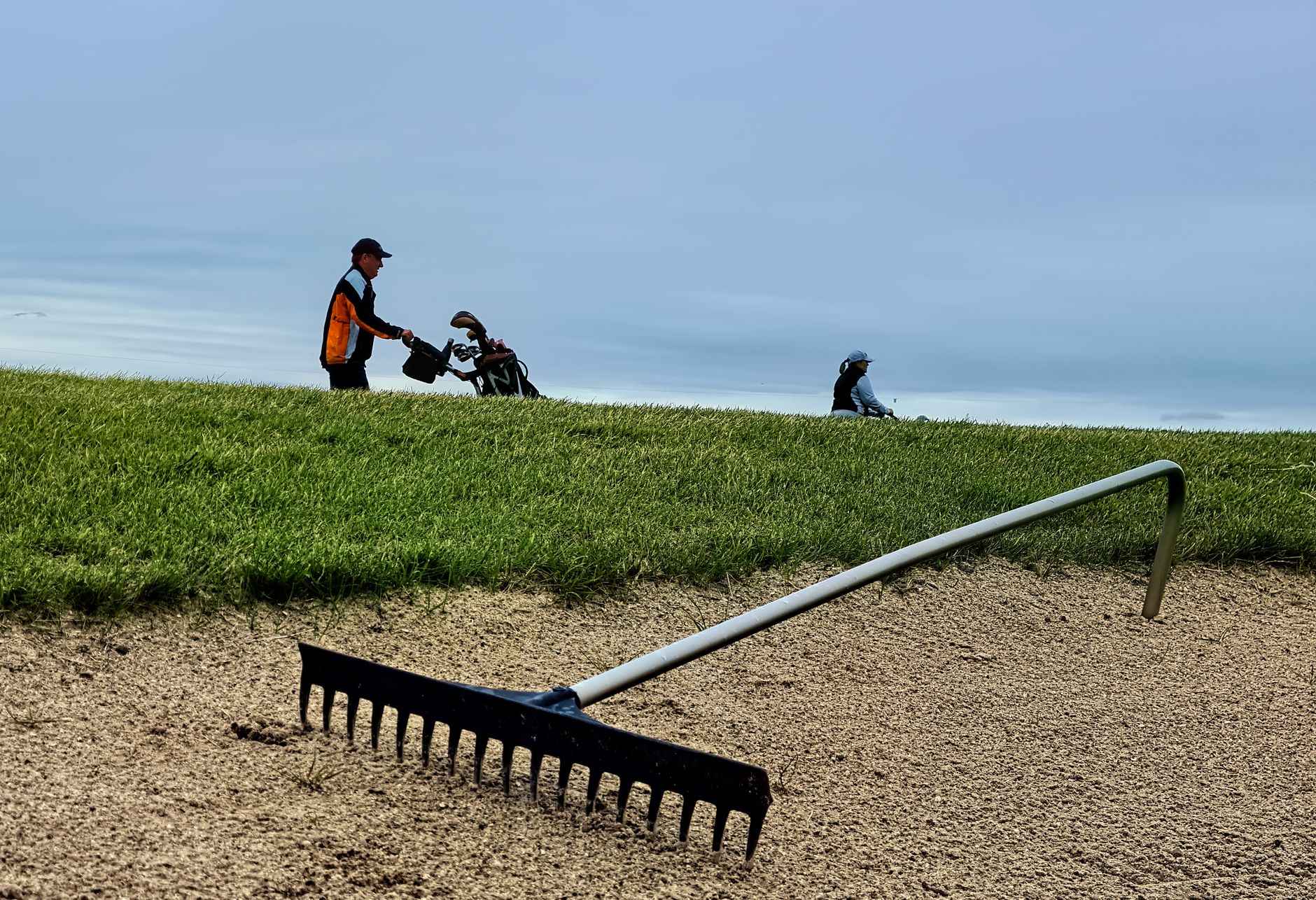 Raked sand in a golf bunker beside manicured turf.