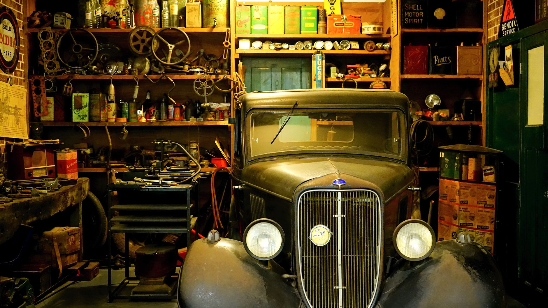 Close view of a garage floor with a drip pan catching engine oil beside an absorbent mat