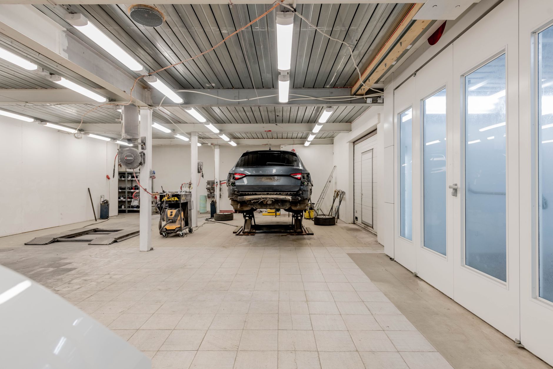 Empty auto repair shop bay with lights dimmed and the floor clear after the crew has gone home