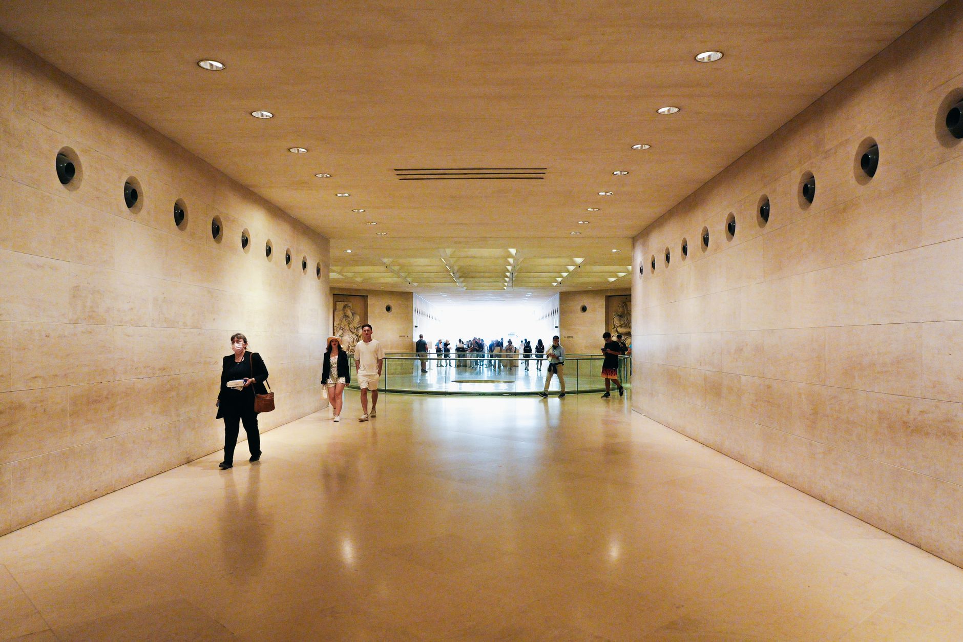 Guests pause along a quiet museum corridor where floor shine and acoustics matter for exhibits.
