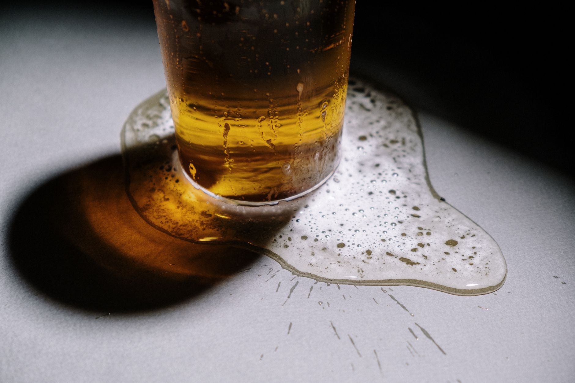A close view of spilled drink residue on a taproom-style floor, showing the sticky film and slip risk discussed in the article.