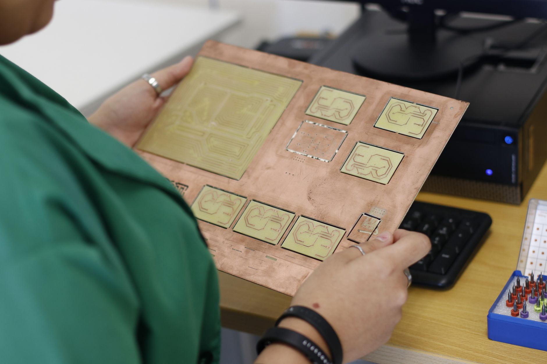 An employee performs a detailed quality inspection on an electronics component, representing the kind of value-added, less physically demanding work available after cobot integration.