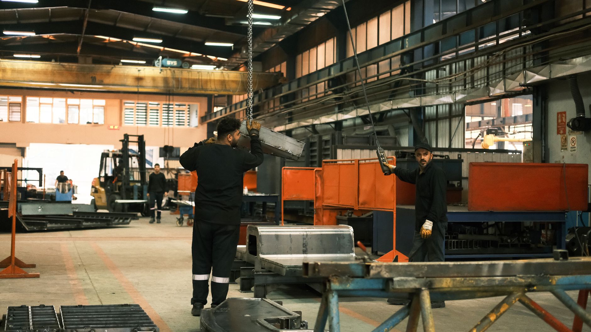 A factory worker strains to lift a heavy box, illustrating the type of ergonomic risk that OSHA's 2026 focus aims to mitigate.