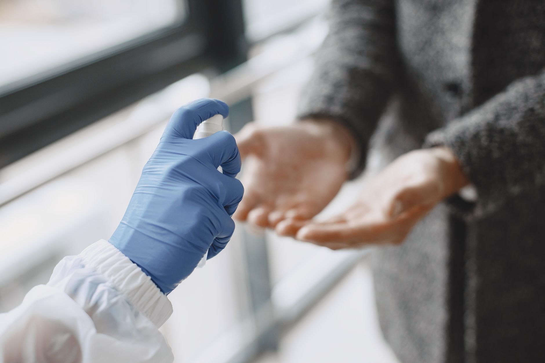 A member of staff wiping down high-touch surfaces in a clinical area with an approved disinfectant.