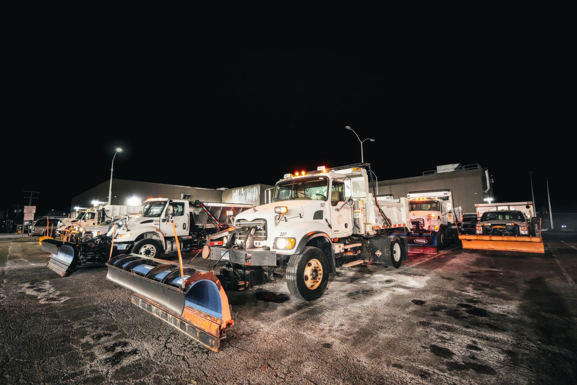 Snowplows parked at a municipal depot where seasonal conditions affect patrol routes.