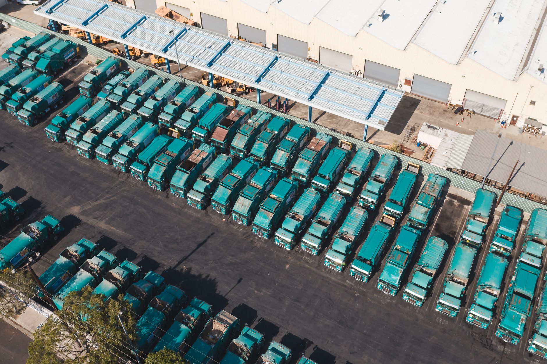 Municipal public works trucks parked in a fenced depot yard.