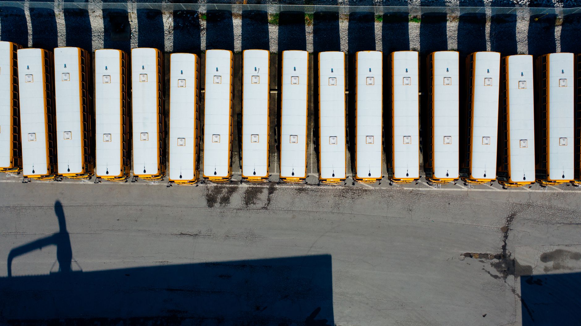 Rows of yellow school buses parked in a district transportation yard at dusk.