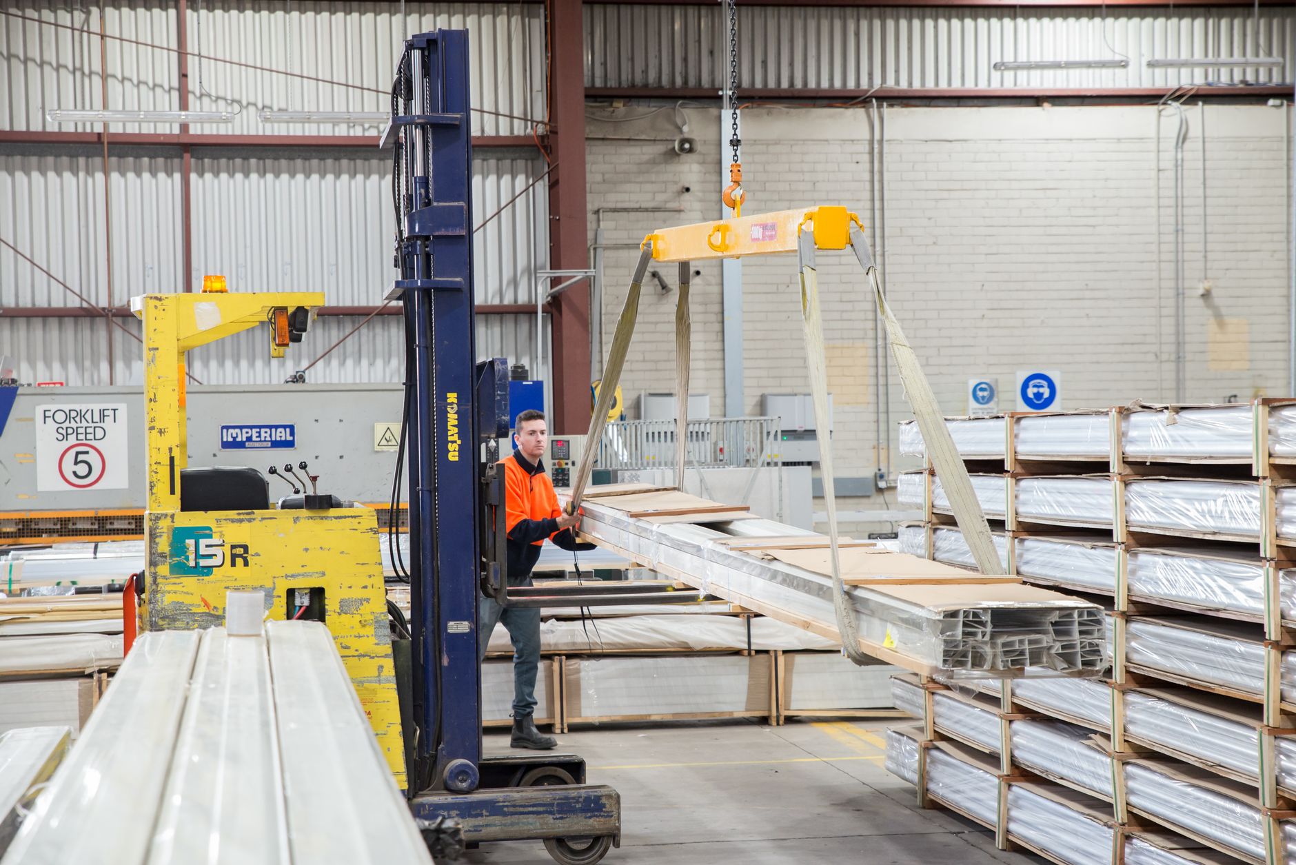 A gloved worker handles sheet-metal parts whose thin edges require careful hazard assessment.