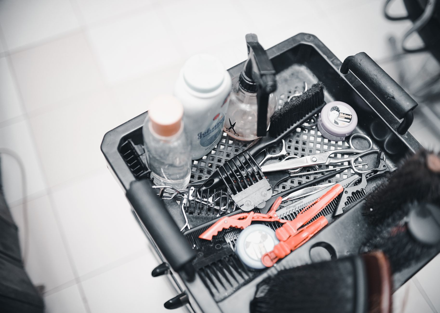 Hair clippings swept across a salon floor tile between styling stations.