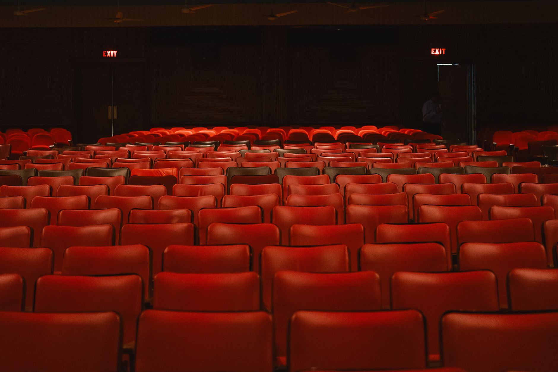An empty movie theater auditorium with rows of seats facing the screen, ready for the overnight cleaning process.