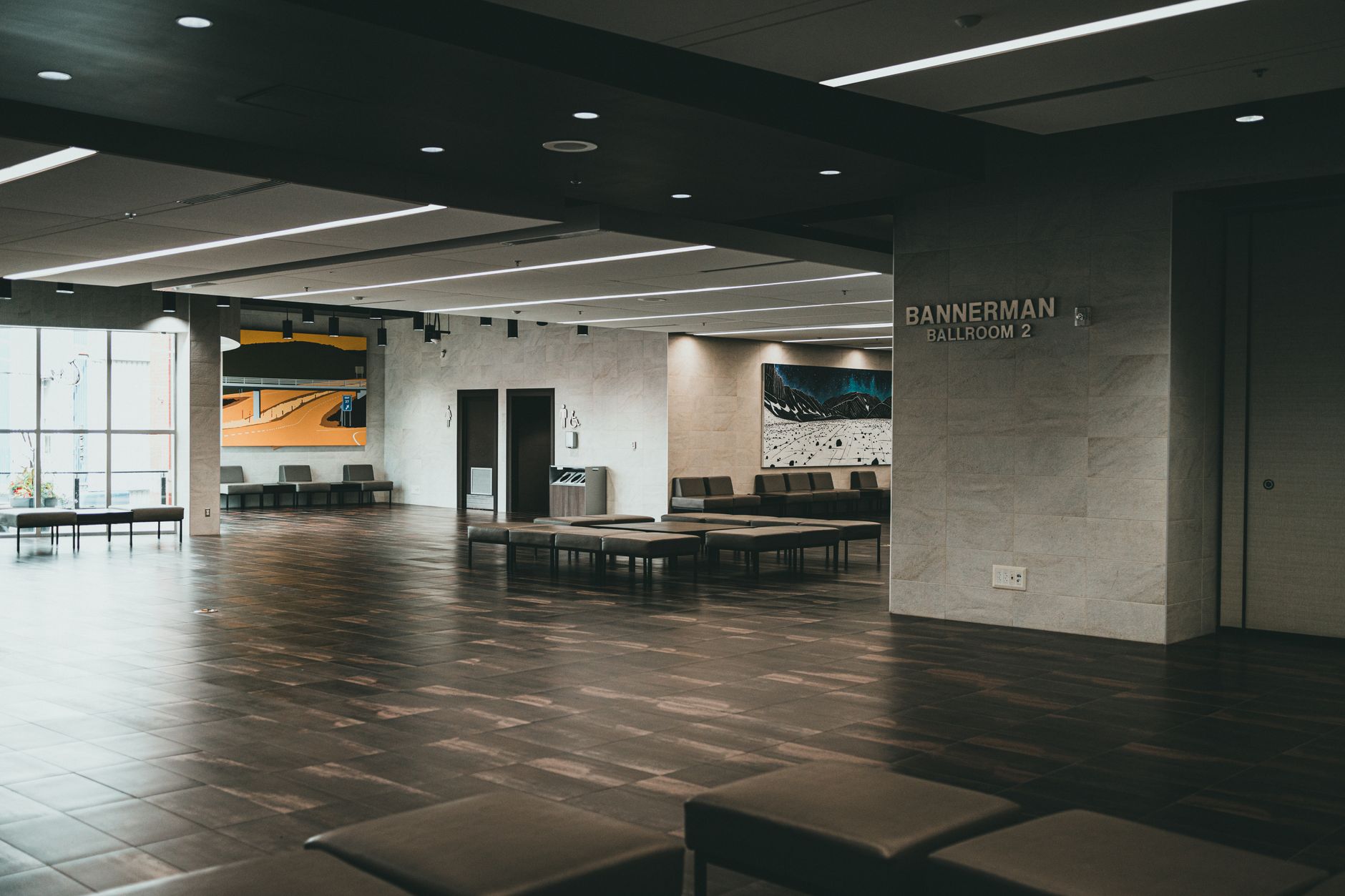 Empty banquet hall with hard floor and tables stacked along the side.
