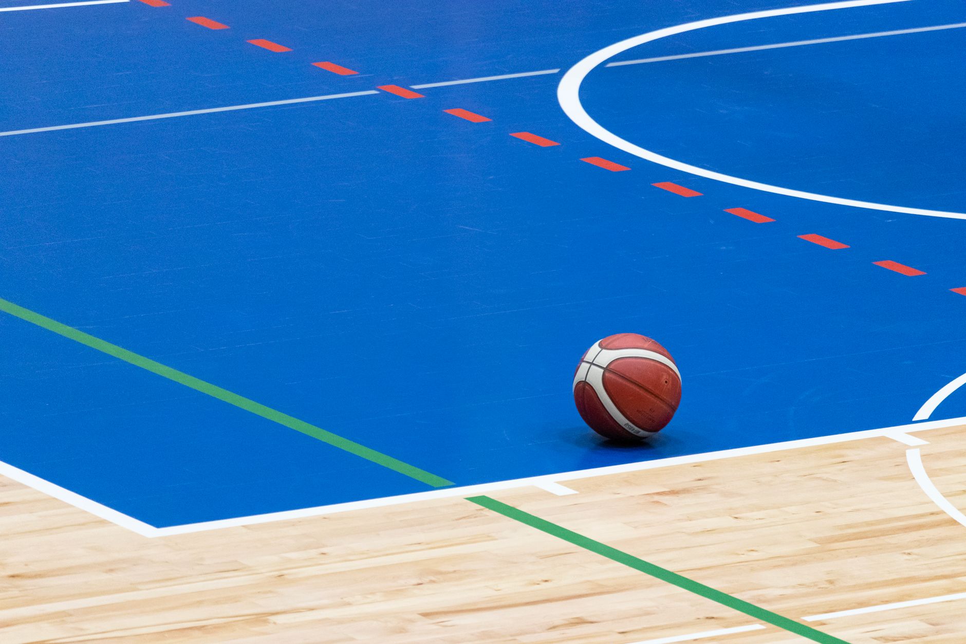A gleaming, empty gymnasium with a polished wood floor, illustrating one of the specialized surfaces a multi-purpose cleaning robot can handle.