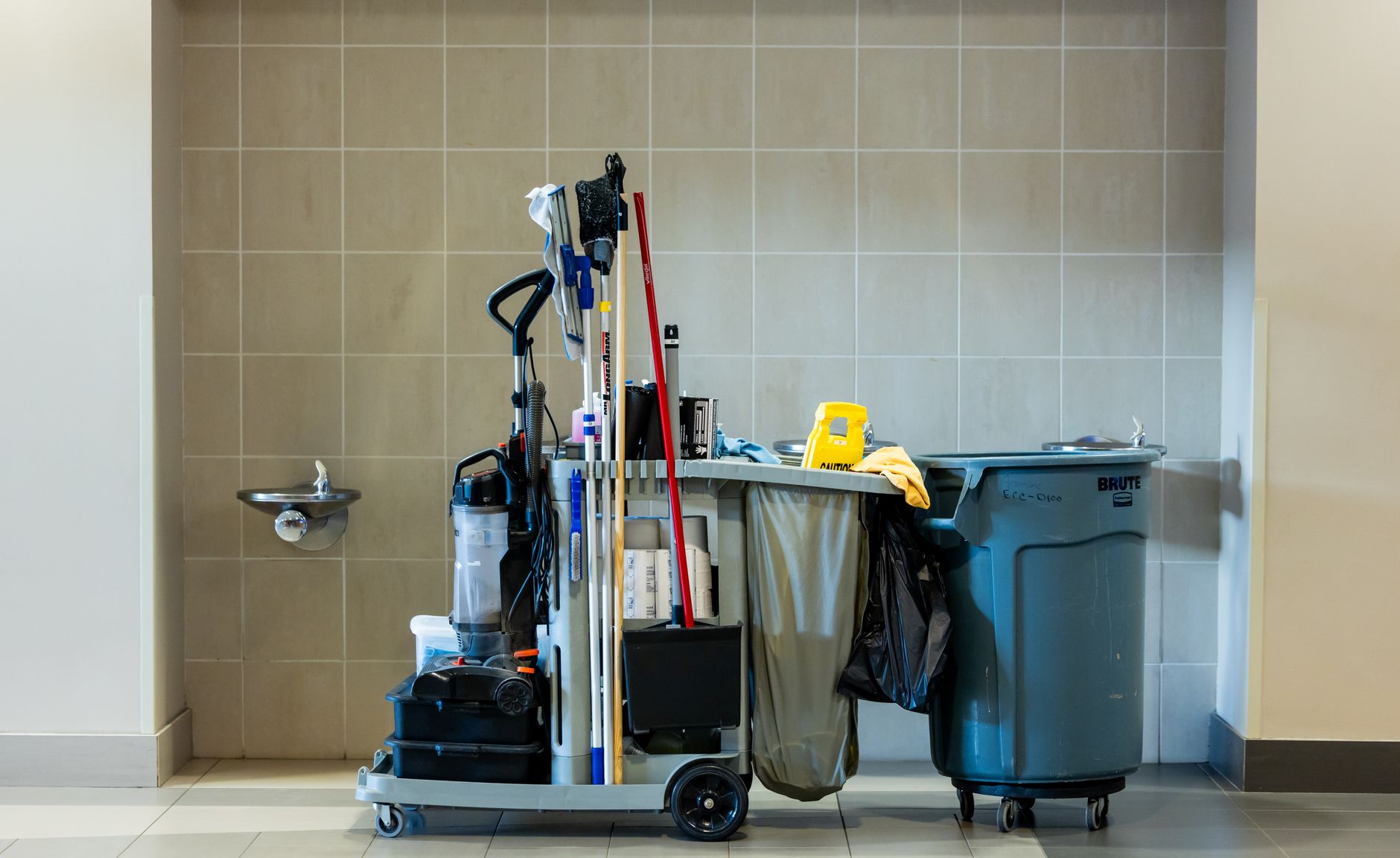 A mop and bucket beside a workbench where manual cleanup still beats an automated route.