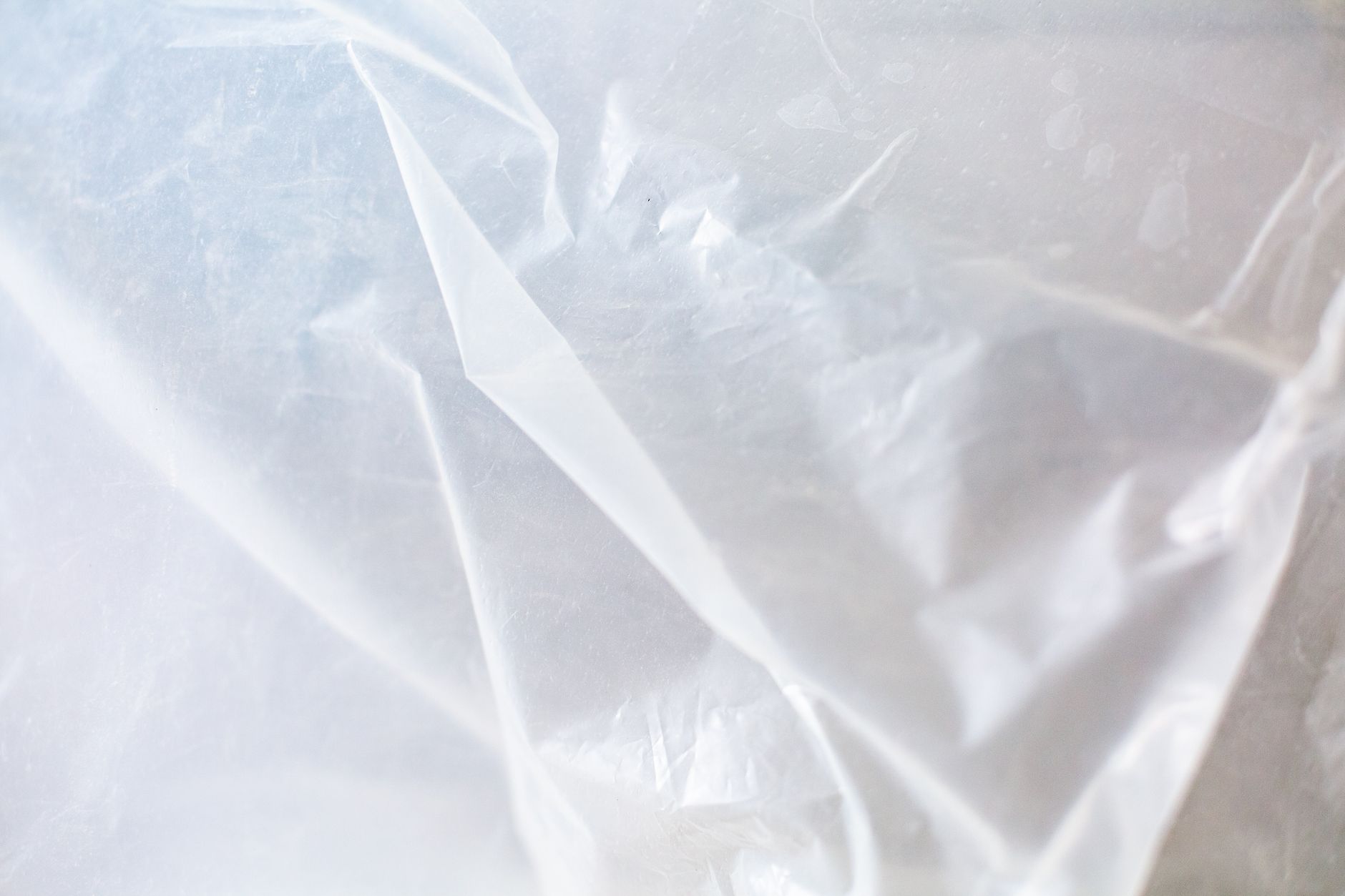 Protective plastic sheeting contains dust around an indoor building-maintenance work area.