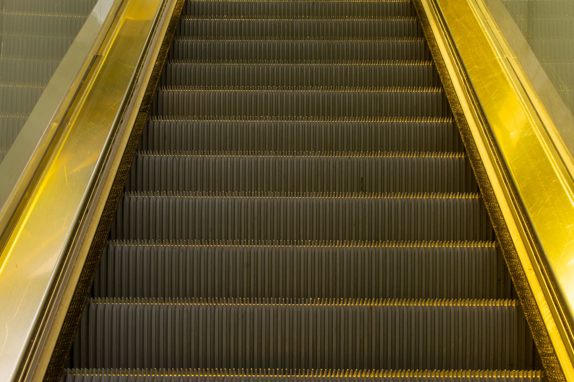 A maintenance technician examines an opened escalator access area before beginning inspection work.