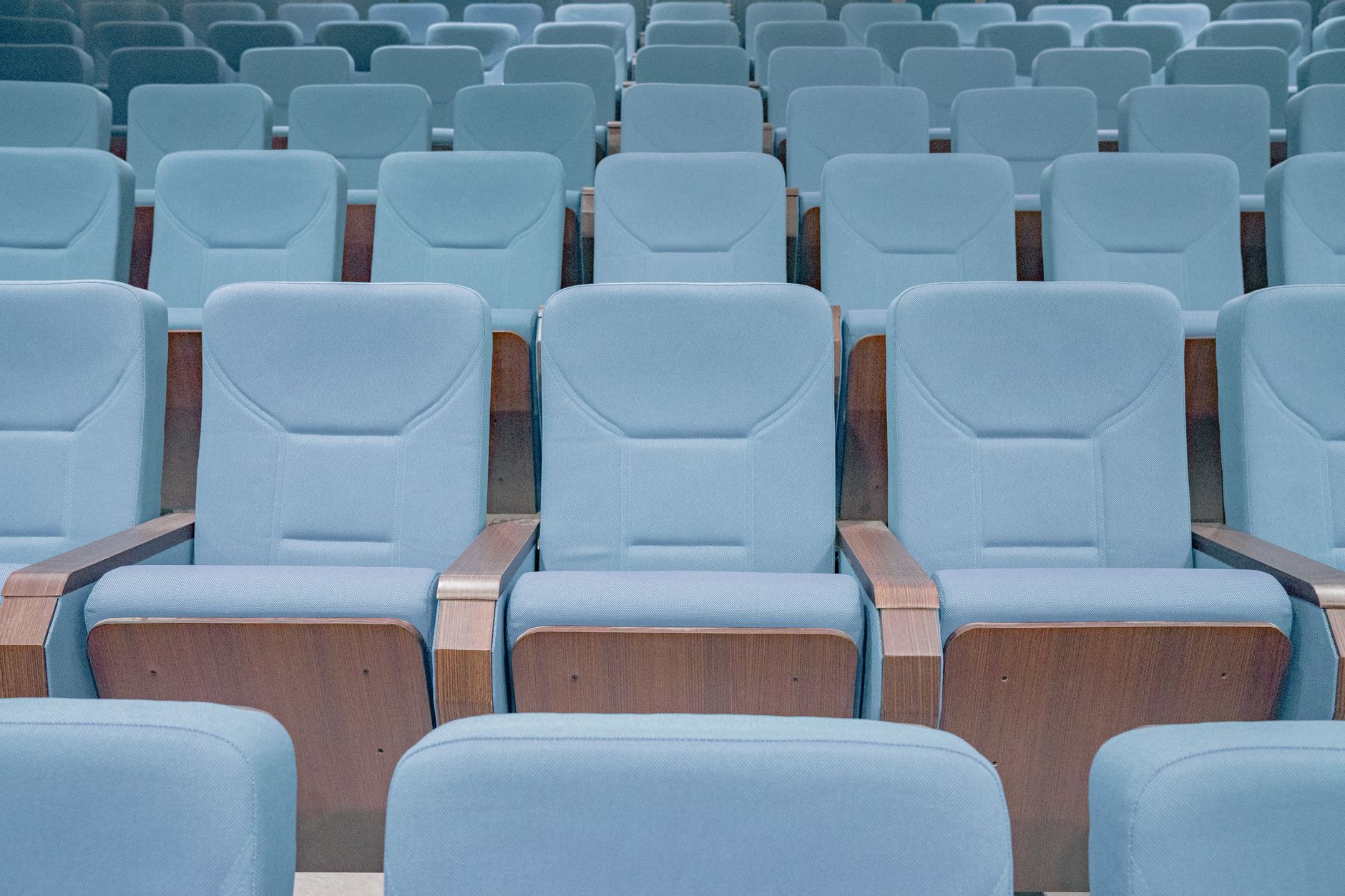Curved rows of fixed planetarium seating descend through a dark, stepped theater bowl.