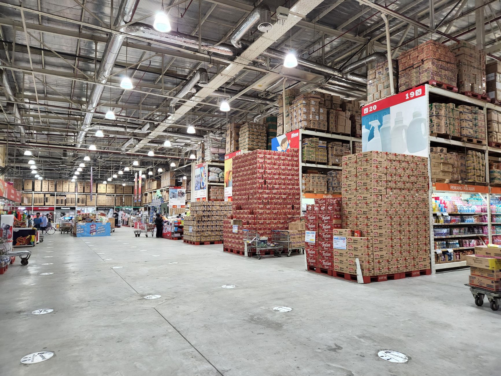 Wide aisles inside a wholesale club with palletized merchandise, showing the kind of broad overnight cleaning lanes that work best when the floor stays clear.
