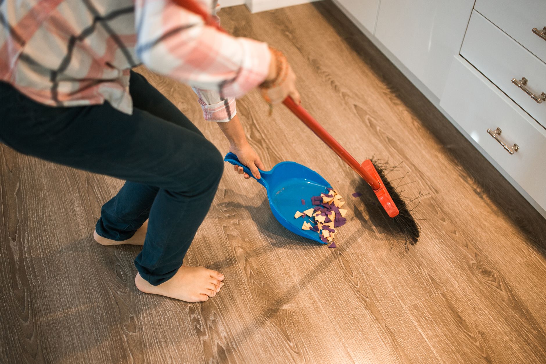 Crew member sweeping dry debris from a hard floor, the kind of pickup best suited to repetitive aisle passes.