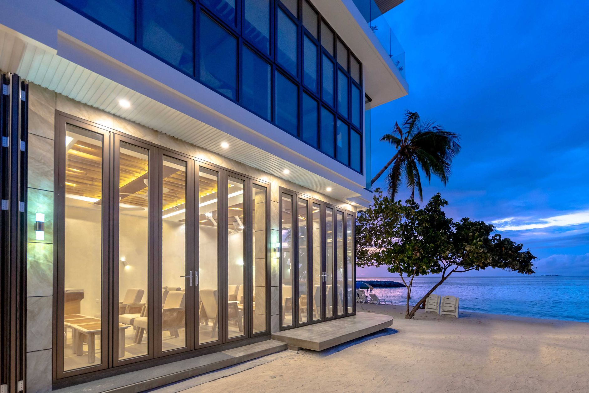 An open-air beachfront resort lobby with tiled floors leading toward the beach.