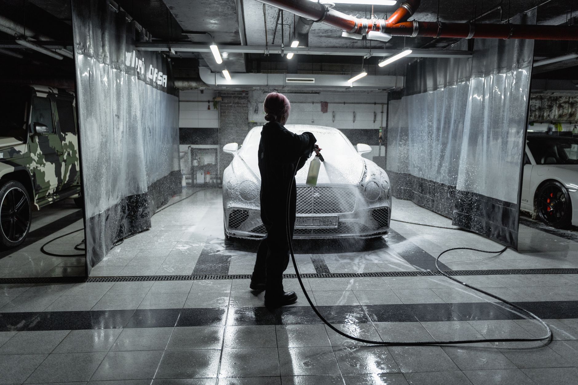 A worker uses a hose to wash a commercial floor during a scheduled cleaning period.
