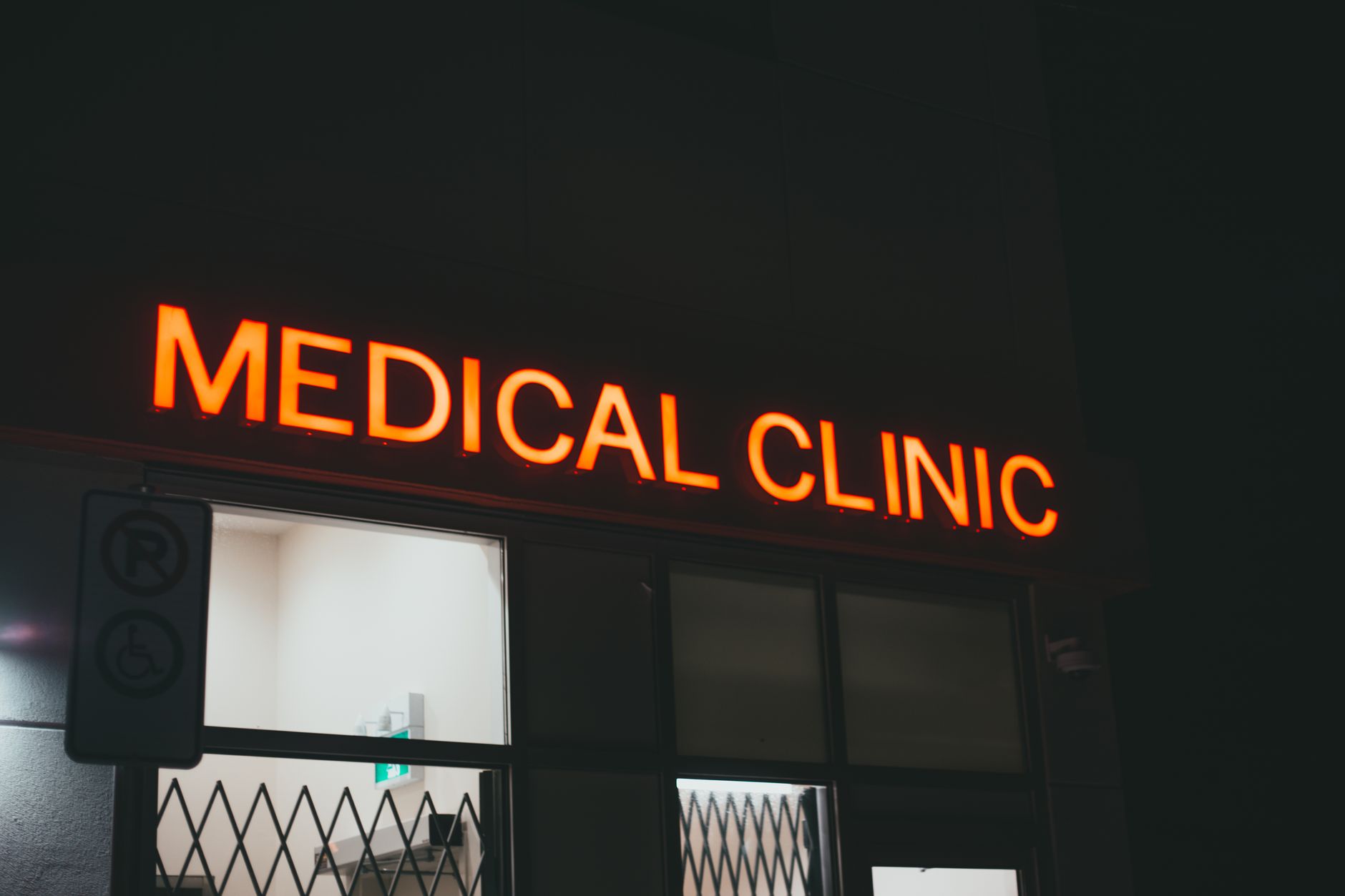 Exterior view of a small urgent care clinic lit up after dark, matching the article's focus on after-hours operations.
