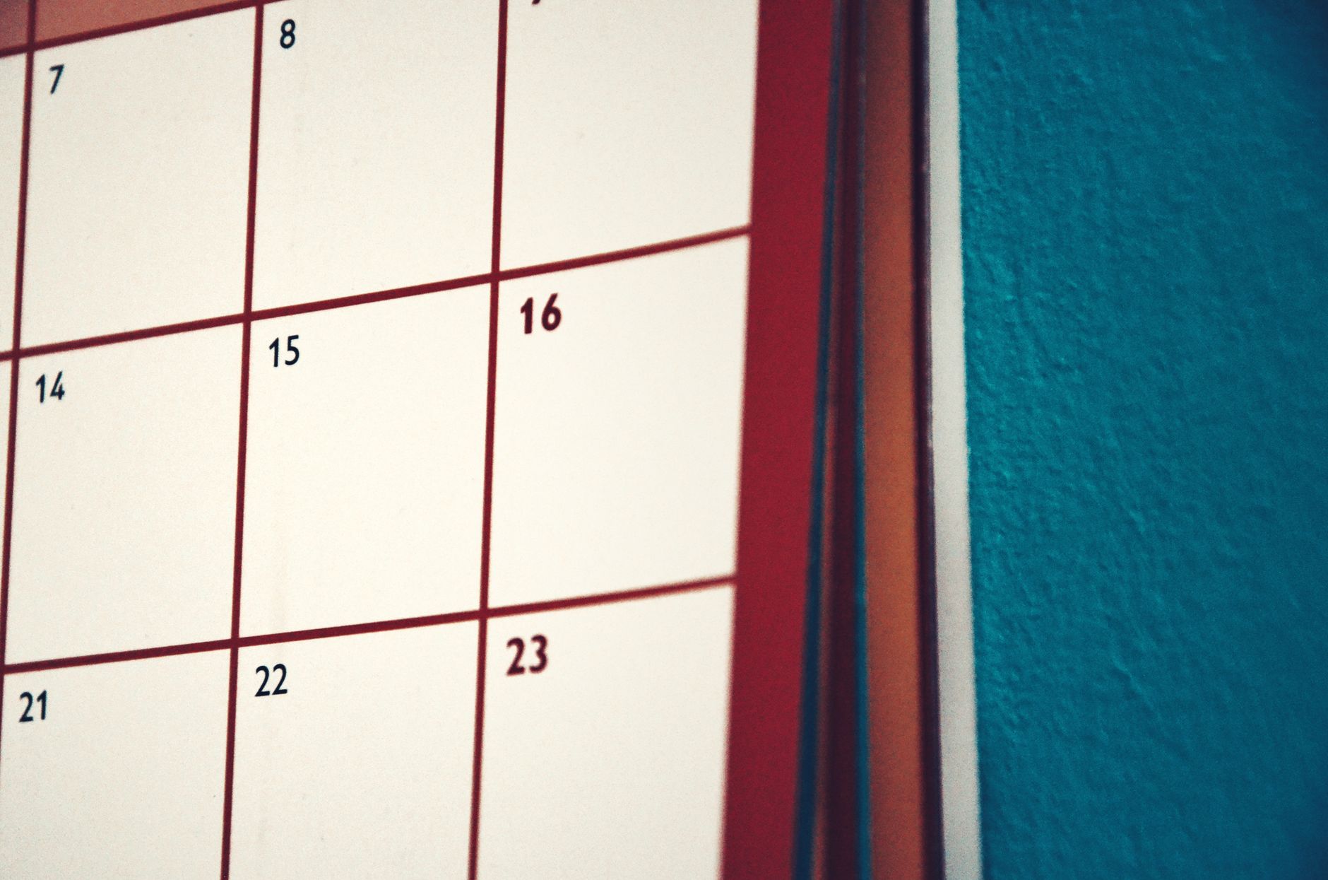 Paper calendar with handwritten notes beside a pen on a desk.