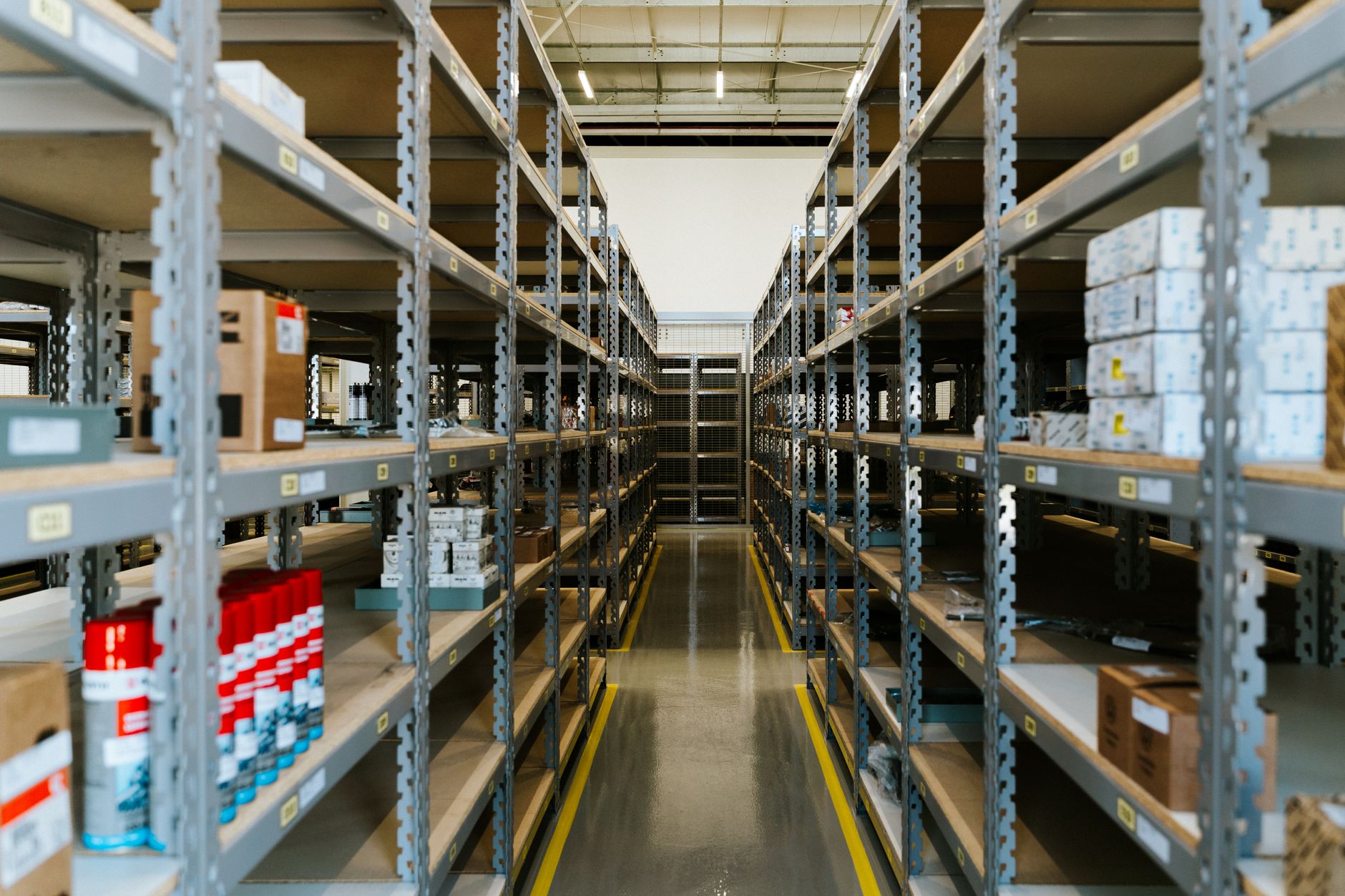 A wide aisle in a modern warehouse, an environment where autonomous mobile robots face cybersecurity threats.