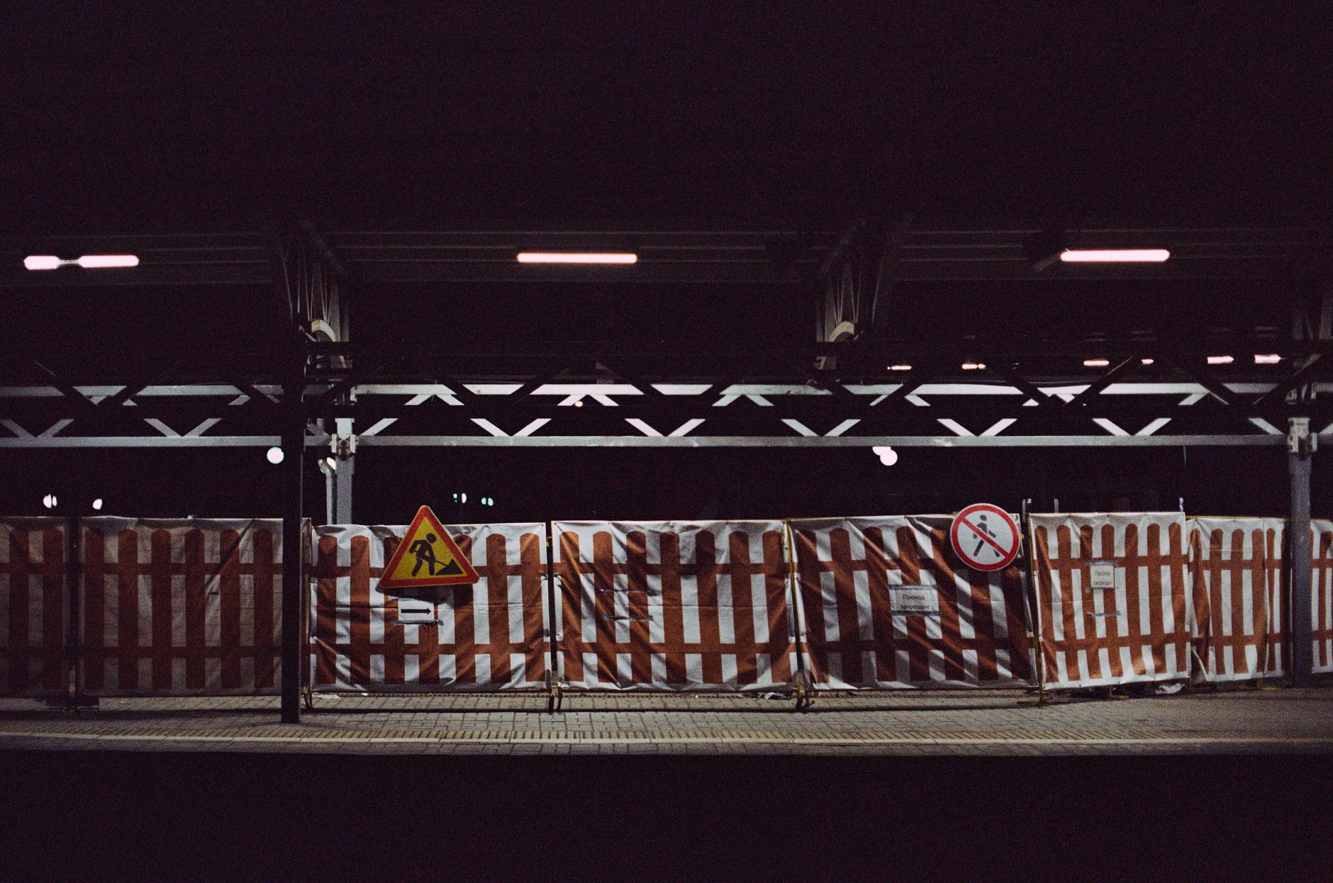 Temporary construction fencing and a dimly lit perimeter at night, showing the kind of shifting boundary that makes active jobsites different from finished facilities.