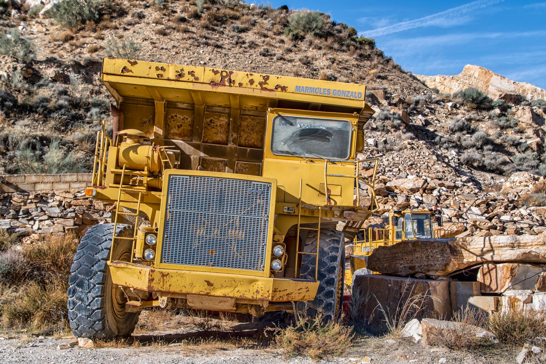Idle haul trucks and stockpiles at an aggregate quarry after the working shift ends.