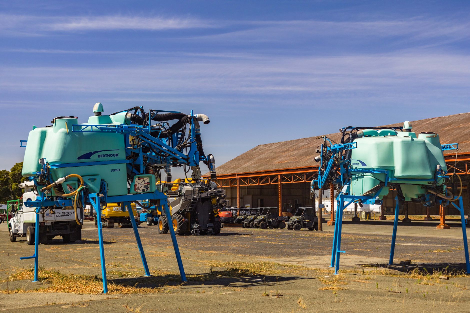 Rows of tractors and large farm implements parked across an outdoor equipment dealer lot.
