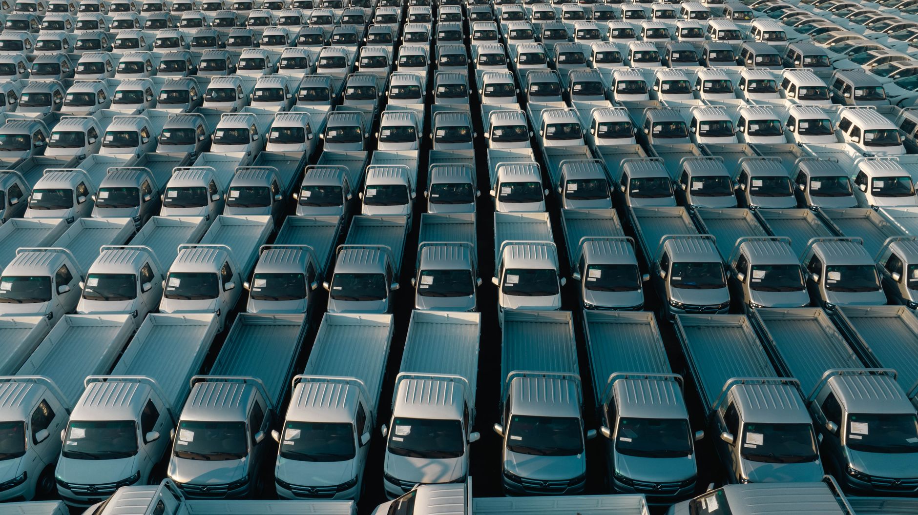 Production trucks and equipment trailers creating narrow lanes and changing sight lines in a busy lot.