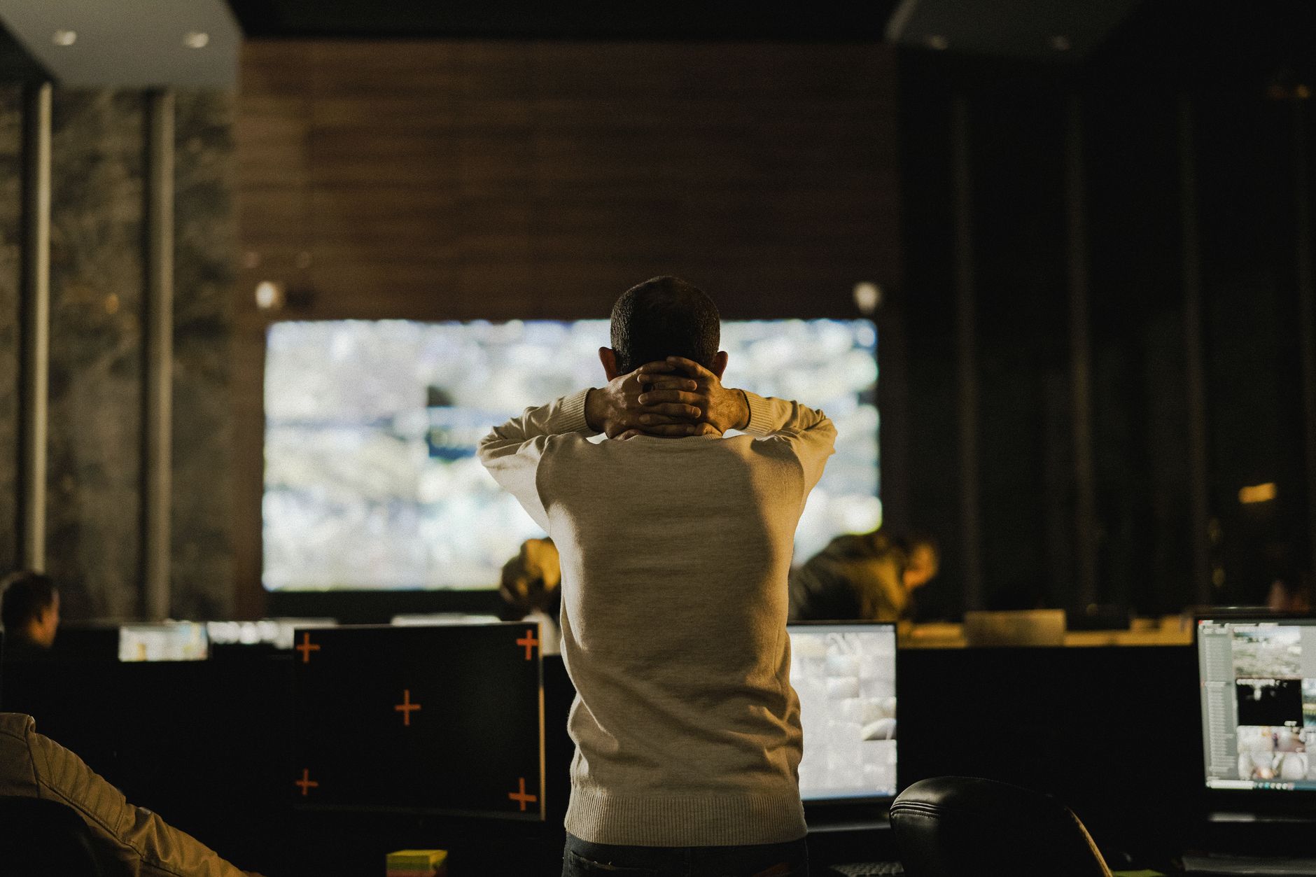 A security operations desk with surveillance screens, representing the human team that receives alerts and manages escalation across a large yard.