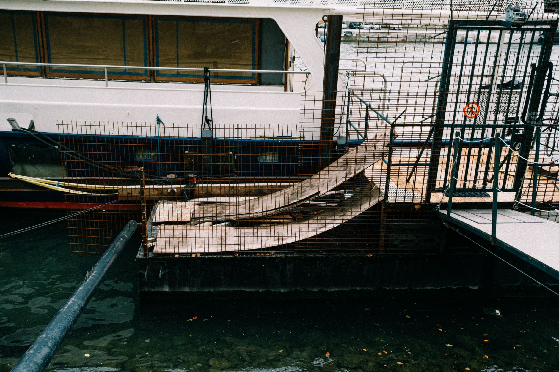 A wet marina gangway and dock access path at low light, illustrating the unstable edges and changing geometry that make waterfront patrol routes harder than inland sites.